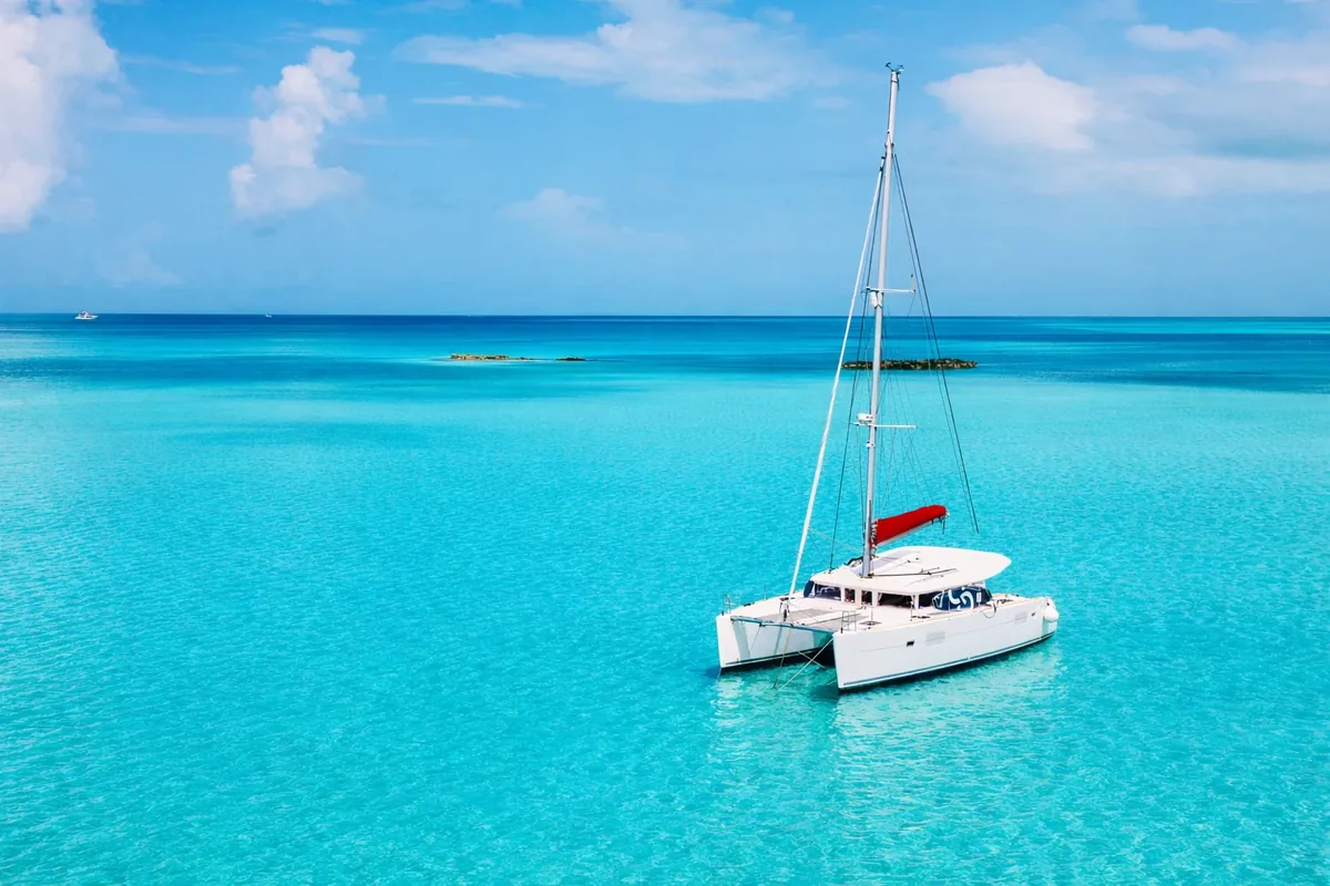 Catamarán CARAMBA Lagoon 421 anclado en aguas turquesas de Ibiza con visibilidad del casco completo